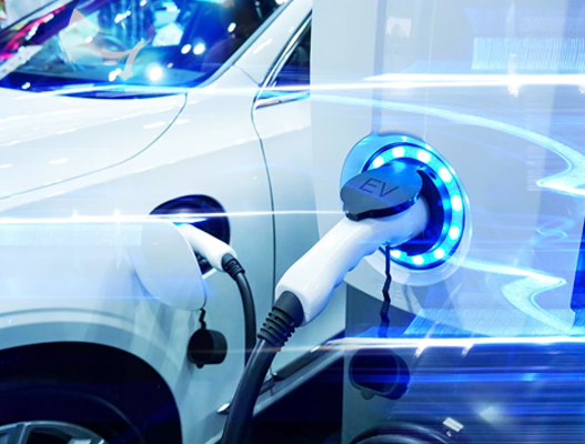 White electric vehicle attached to blue light up electric vehicle charge point